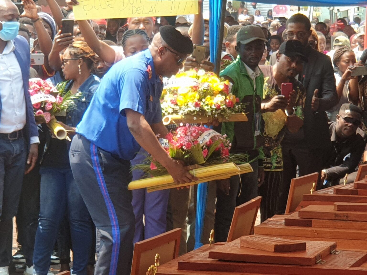 LE GOUVICE DEPOSANT LA GERBE DE FLEURS DEVANT LES CORPS DES PERSONNES TUEES AU COURS DE LA MARCHE ENTI MONUSCO